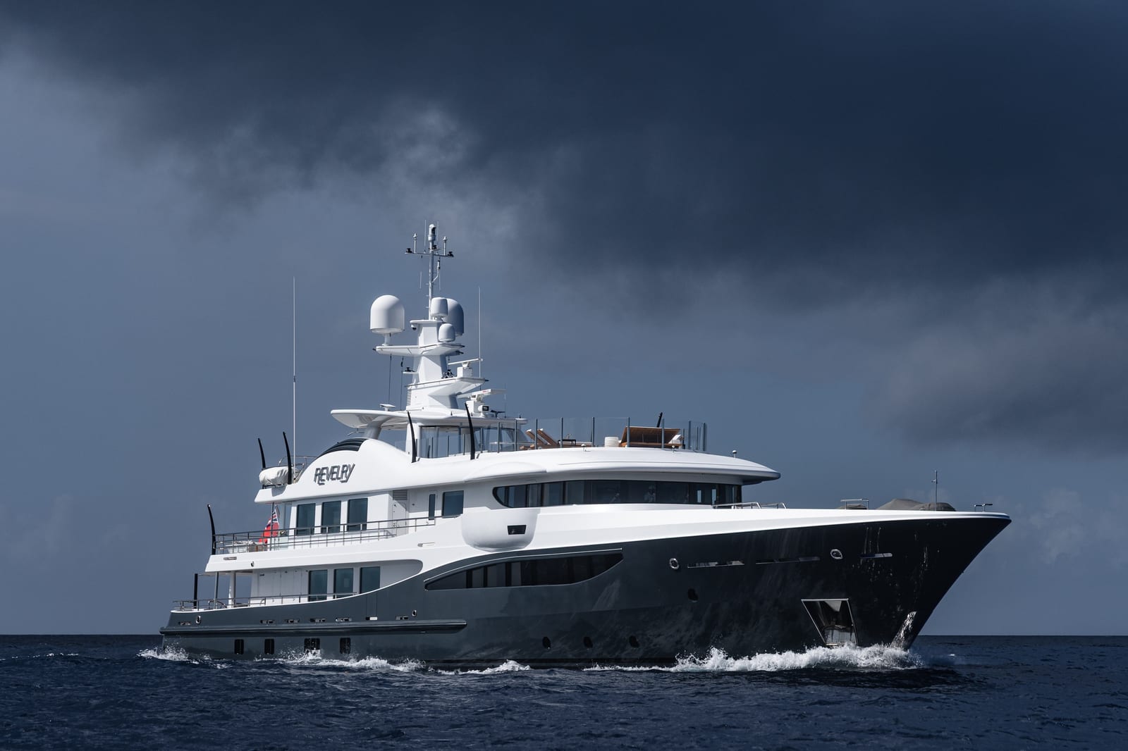 Revelry lit by a break in the clouds against a dark storm sky, a dramatic yacht photograph