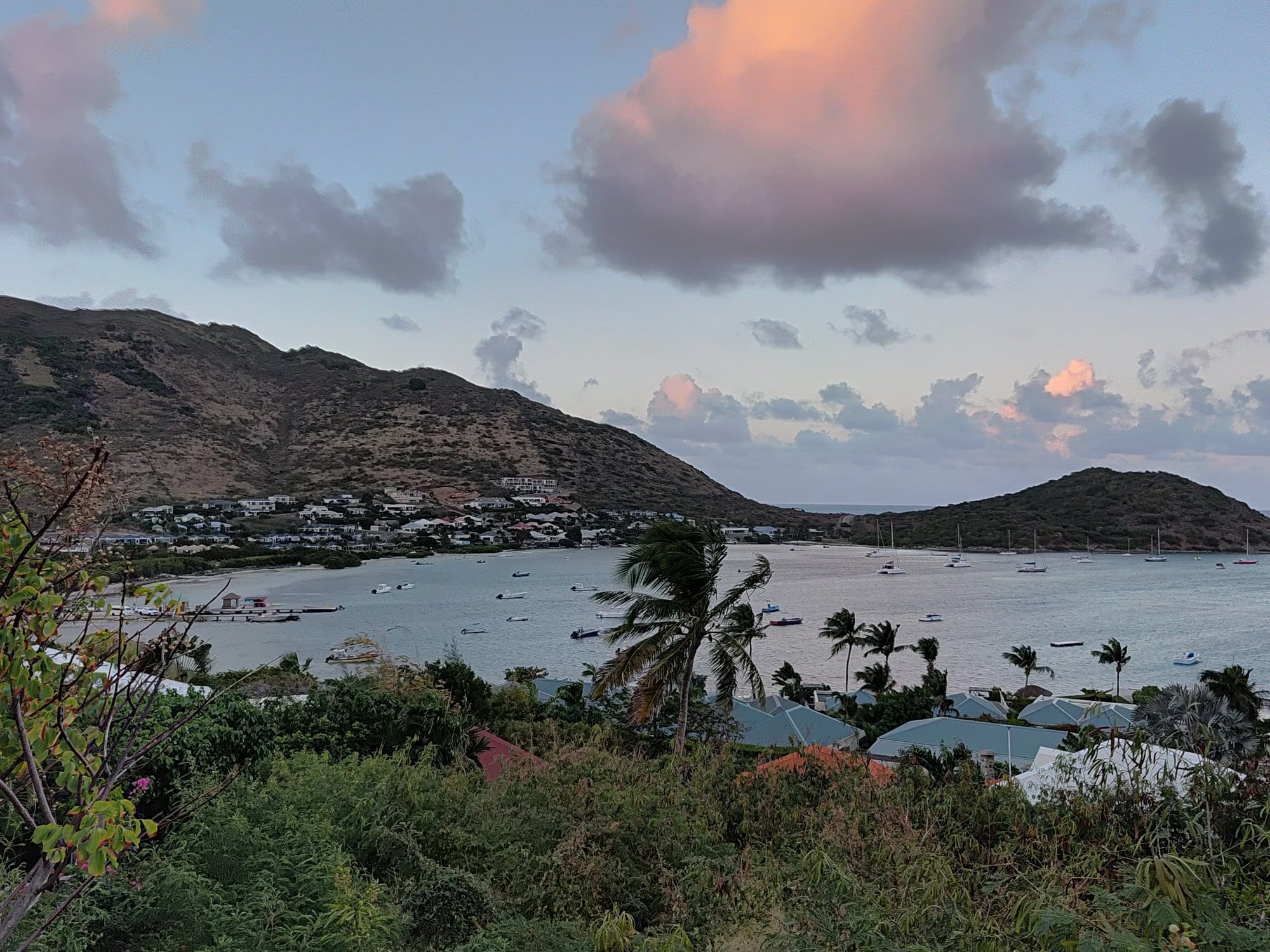 Bay on St Maarten at dusk, with yachts at anchor below green hills