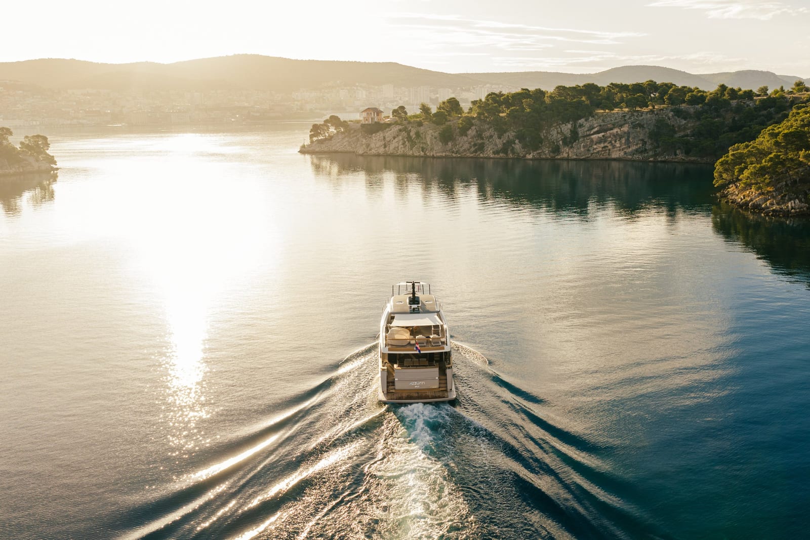 Yacht underway into the sun in a calm Croatian bay at golden hour
