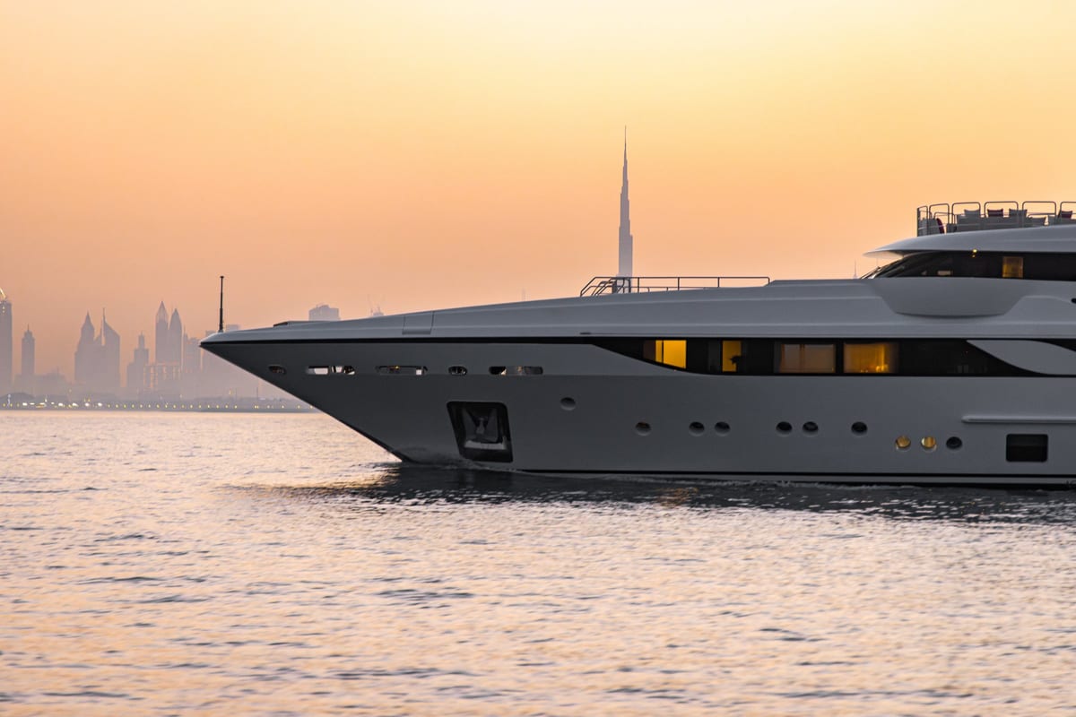 Close view of a superyacht bow with the Dubai skyline in the haze