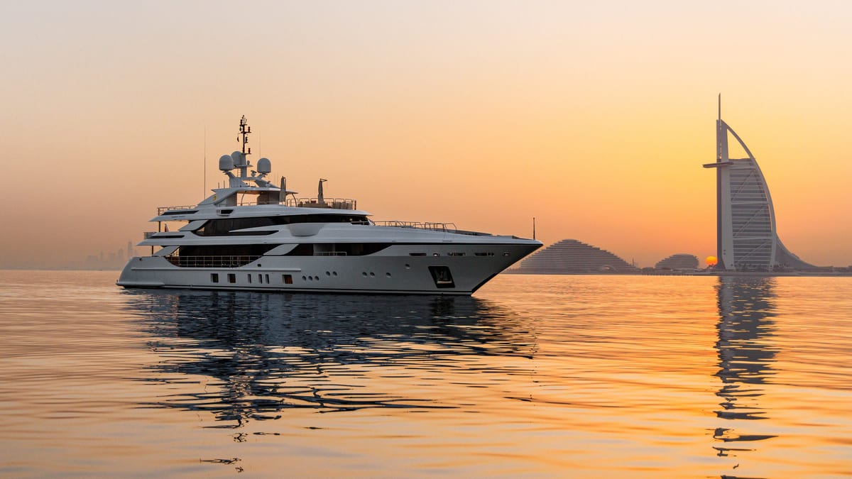 Superyacht underway at sunset with the Burj Al Arab on the horizon