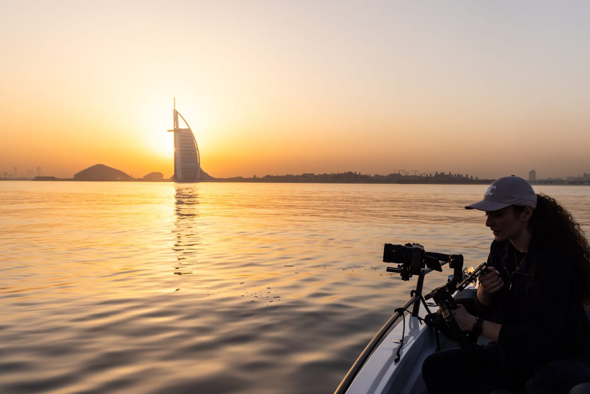 Our camera operator filming from a chase boat as the sun sets behind the Burj Al Arab