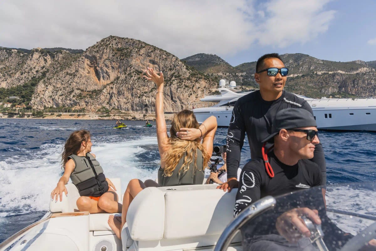 Guests in life jackets enjoying a fast tender ride near rocky cliffs.