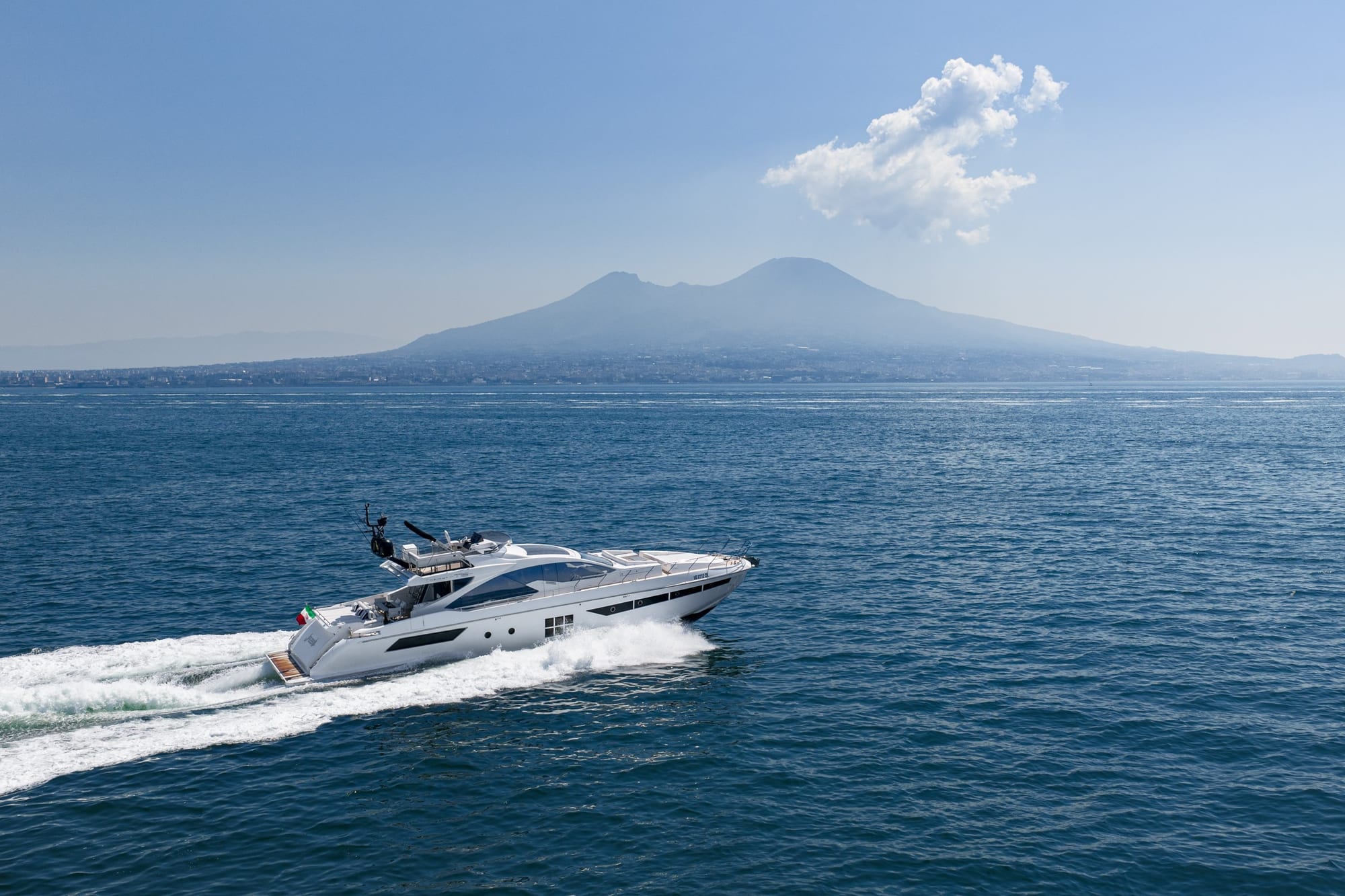 Motor yacht running across the Bay of Naples with Mount Vesuvius behind