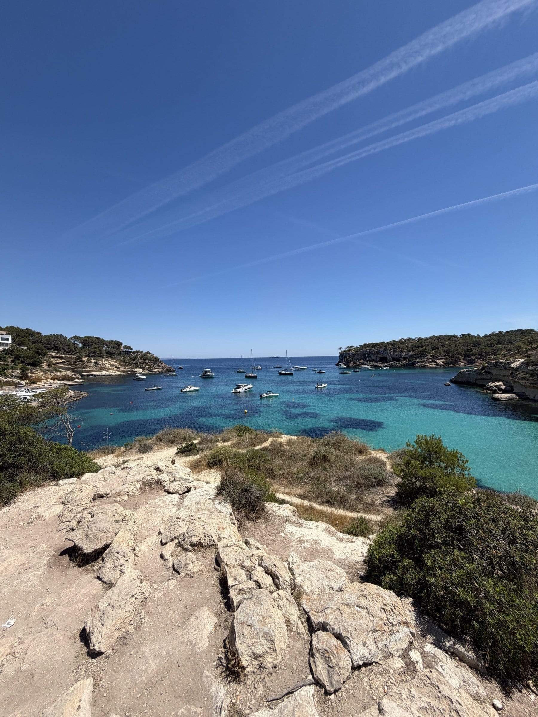Yachts anchored in a long turquoise cove on Mallorca, seen from the clifftop