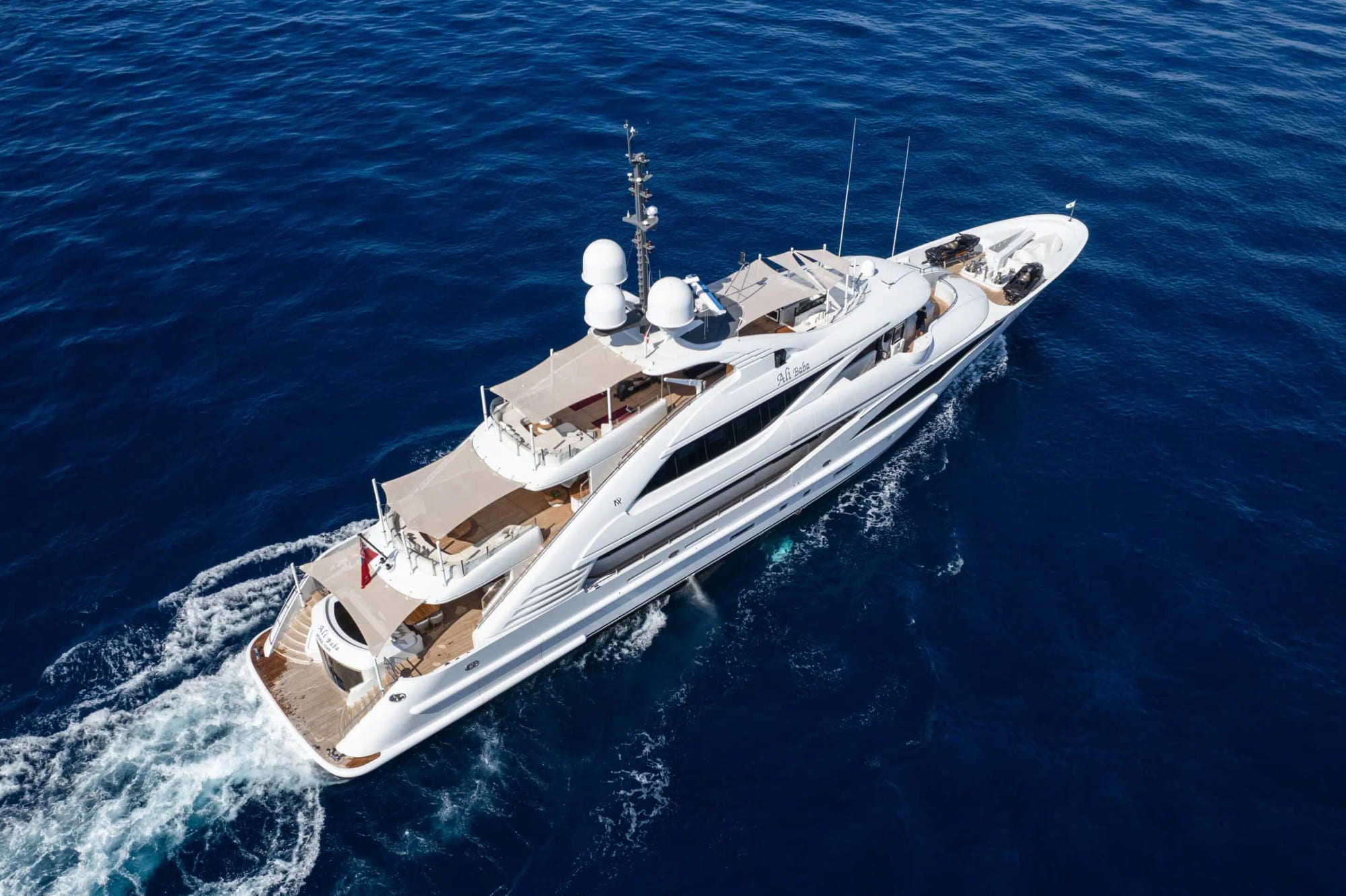 Aerial view of a white superyacht underway on deep blue water